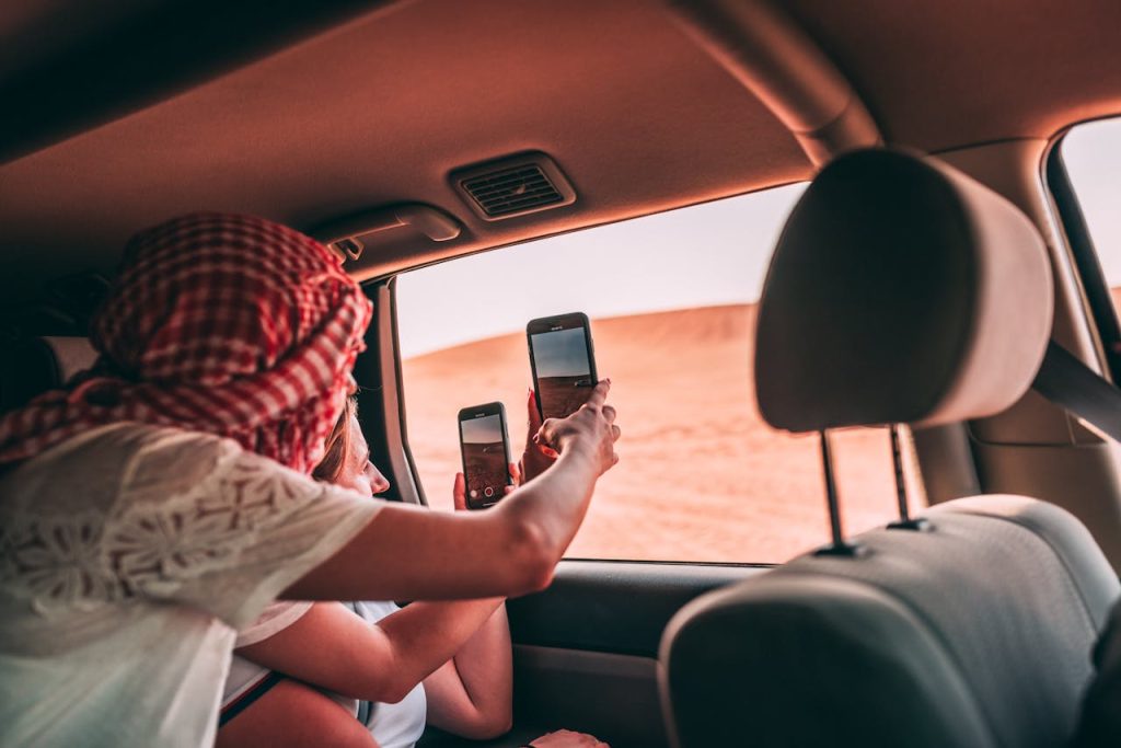 Tourists taking photos from inside a car in Dubais desert landscape.