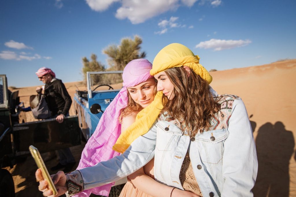 Two young tourists taking a selfie in a desert safari, capturing a memorable travel moment.